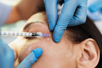 Attractive woman is getting a rejuvenating facial injections at beauty clinic. The expert...