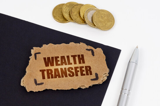 On A Black And White Surface Lies A Pen, Coins And A Cardboard Sign With The Inscription - Wealth Transfer