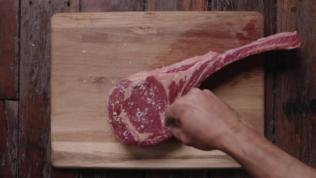 Tomahawk steak being salted