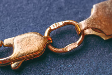 Gold 585 stamp. Gold clasp of a golden bracelet with hallmark 585. It is a type of gold, known as 14K gold. Macro photography. Cropped image. - obrazy, fototapety, plakaty