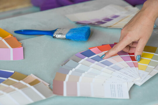 The hands of a female designer choosing paint samples for walls. A girl looks at a color sample to create a project. Reconstruction of the house, the concept of architecture and interior design.