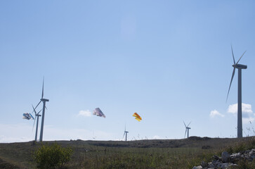 Colorful kites driven by the wind with wind turbines, a symbol of wind and renewable energy