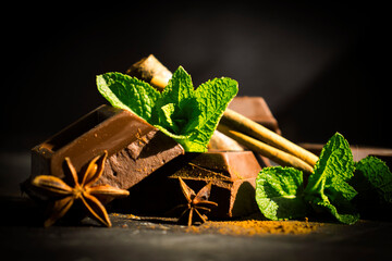 Black chocolate, mint leaf on a dark background