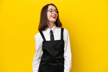 Young Ukrainian waitress woman isolated on yellow background laughing in lateral position