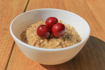 Oatmeal with cherries close-up on a wooden table. Healthy food every morning
