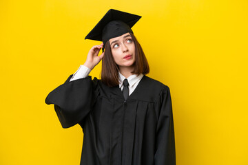 Young university graduate Ukrainian woman isolated on yellow background having doubts and with...