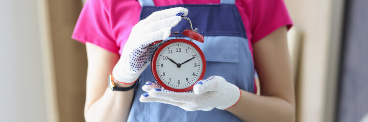 Woman worker in uniform holding red clock reminder to finish work on time
