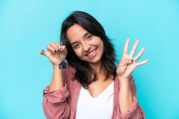 Young hispanic woman holding home keys isolated on blue background happy and counting four with fingers