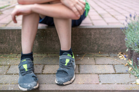 Kleiner Junge mit kaputten Schuhen als Symbol für Kinderarmut Photos |  Adobe Stock