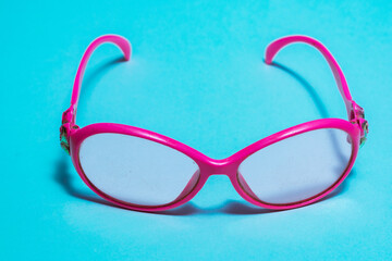 pink sunglasses with scratched lenses, for little girl on blue background. dirty and used...