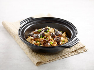 Stewed Diced Sea Cucumber with Tofu in Casserole served in a dish isolated on wooden board side view on grey background