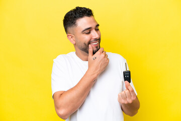 Young Arab man holding car keys isolated on yellow background thinking an idea and looking side