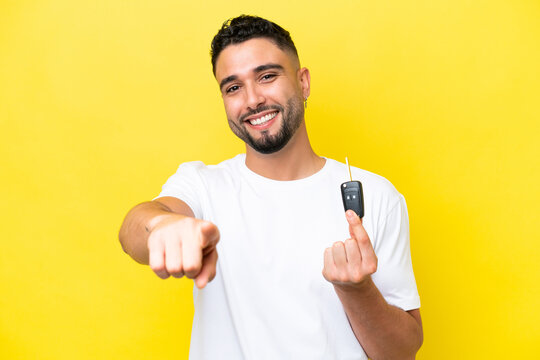 Young Arab man holding car keys isolated on yellow background points finger at you with a confident expression