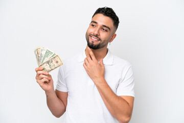 Young Arab man taking a lot of money isolated on white background looking up while smiling