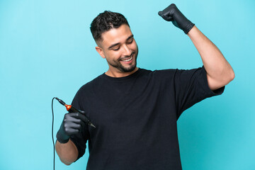 Tattooist Arab man isolated on blue background celebrating a victory