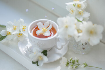 Fototapeta na wymiar Spring still life with a cup of tea and jasmine flowers