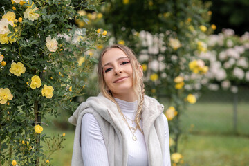 Portrait of a young girl in the garden with yellow roses