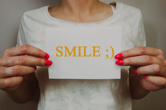 Woman holding paper sheet with word smile