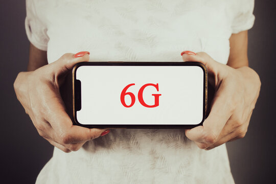 Woman holding phone with text 6G. 6 G high speed communication technology concept