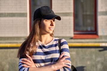 Outdoor portrait of teenage girl in black cap, city street background