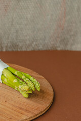 branches of fresh green asparagus on a wooden board, brown background, top view. Basic trend concept with copy space.