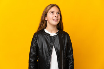 Child over isolated yellow background thinking an idea while looking up