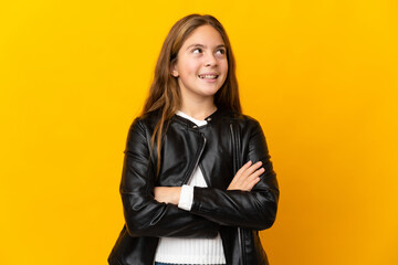 Child over isolated yellow background looking up while smiling