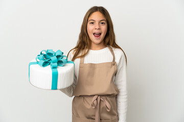 Little girl holding a big cake over isolated white background with surprise facial expression