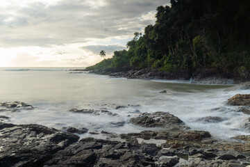 Sunrise with long exposure photograph of the beach with lighthouse on the horizon