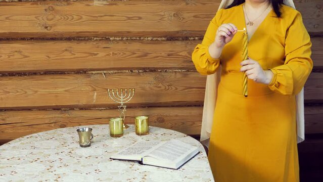 A Jewish woman lights Awdala candles at the end of Shabbat. Overall plan