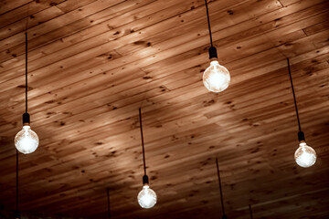 Old incandescent lamps hang on wires on a wooden ceiling. Retro design.