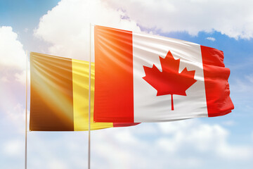 Sunny blue sky and flags of canada and belgium