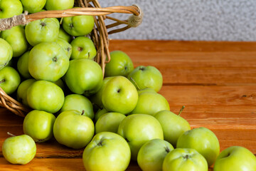 Composition with juicy green apples in wicker basket on table. Copy space