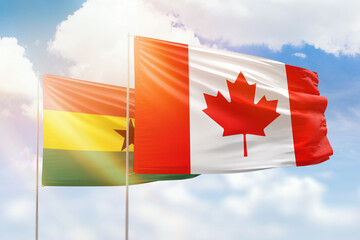 Sunny blue sky and flags of canada and ghana