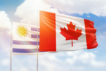 Sunny blue sky and flags of canada and uruguay