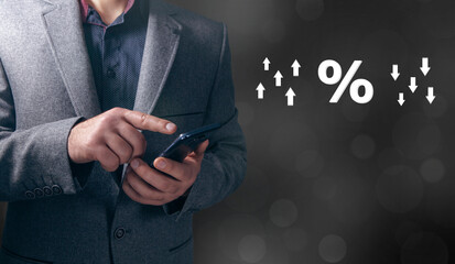 Percent icon with up and down arrows. Man holding a phone in his hand