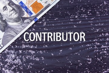 CONTRIBUTOR - word (text) on a dark wooden background, money, dollars and snow. Business concept (copy space).