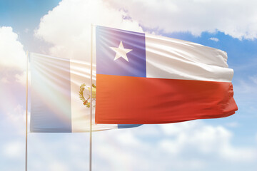 Sunny blue sky and flags of chile and guatemala