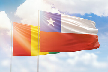 Sunny blue sky and flags of chile and guinea