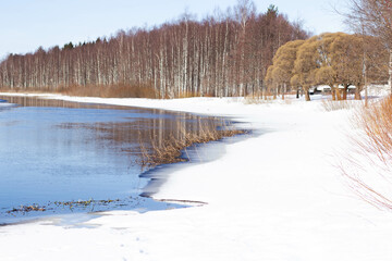 View of the river with ice in the spring. Shores with trees.