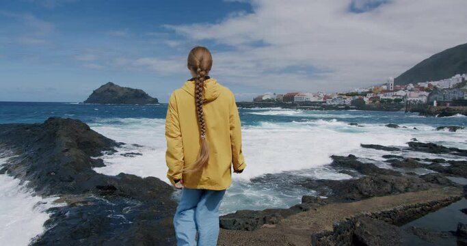 Young woman tourist enjoying the seaside. The girl carefree raiser her arms- Garachico. Tenerife. Canary Islands. Spain