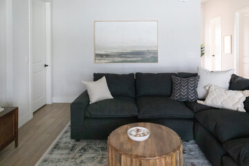 Living room with dark sectional sofa, wood coffee table, and wall art