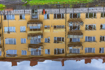 Beautiful blurred view of upside-down reflection in water of yellow building. Sweden. 