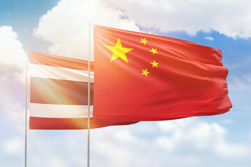 Sunny blue sky and flags of china and thailand