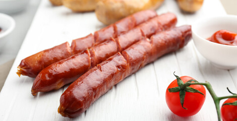 Tasty smoked sausages on wooden board, closeup