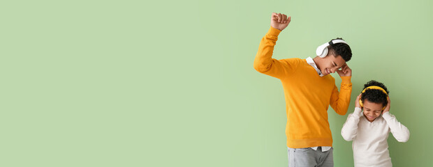 African-American boys listening music and dancing on color background with space for text