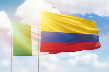 Sunny blue sky and flags of colombia and italy