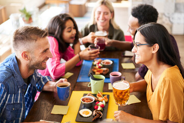People having fun at bar. Friends taking lunch time drinking beer and eating cakes. Lifestyle and community concept with happy men and women at cafe bar