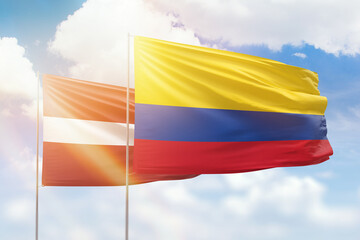 Sunny blue sky and flags of colombia and latvia
