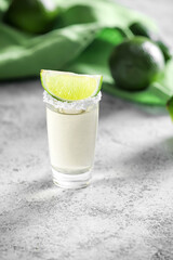 Shot of tasty mexican tequila with lime on grey background